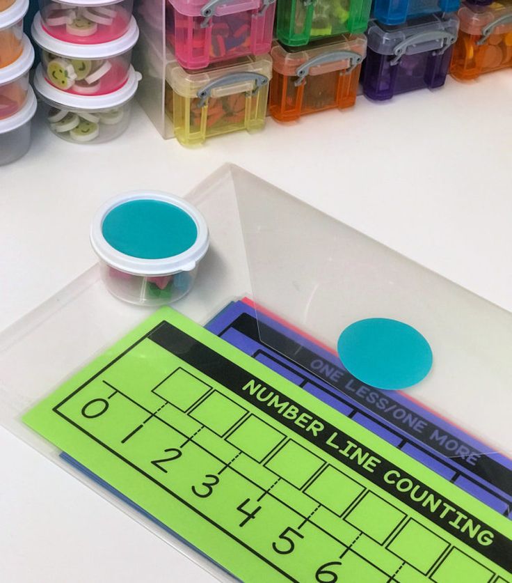 a number line counting game with plastic cups and markers on the table next to it