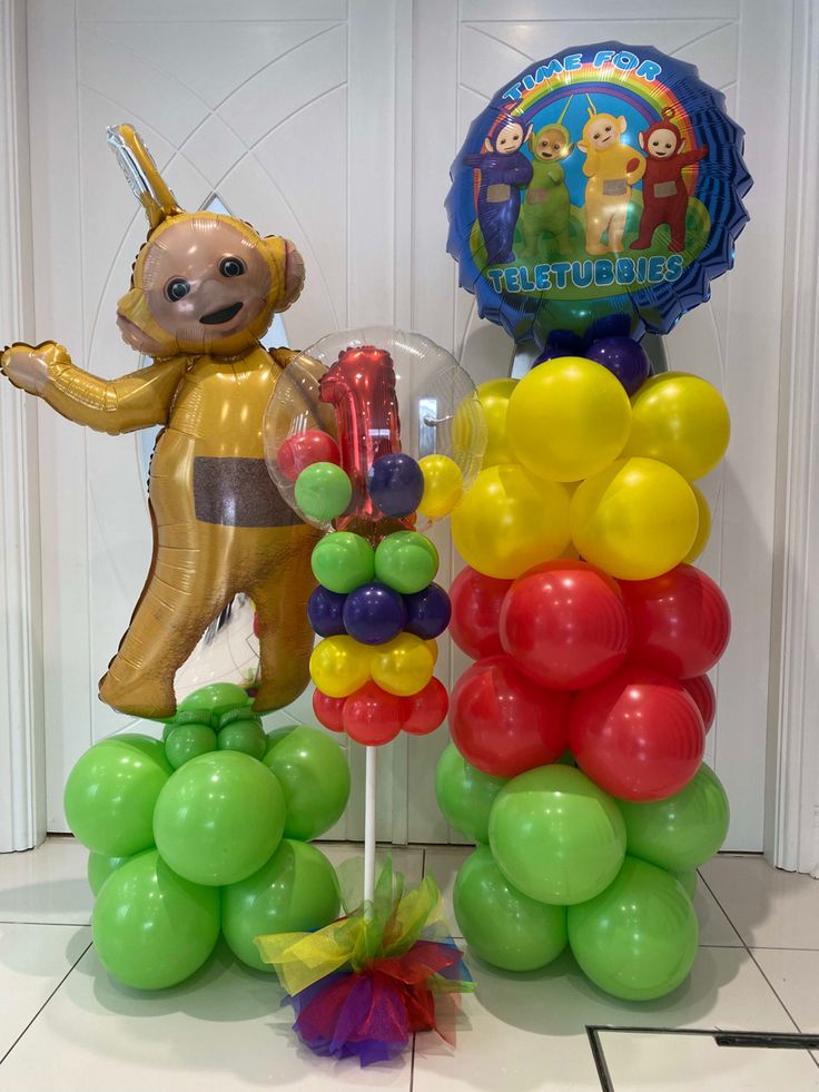 there is a balloon tower with balloons and a teddy bear on top that says happy birthday