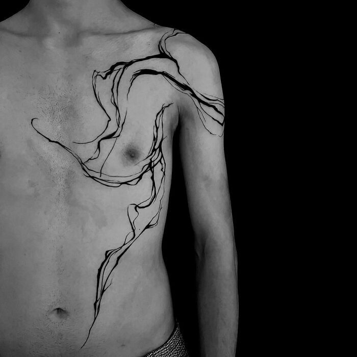 a black and white photo of a man's chest with an artistic tattoo on it