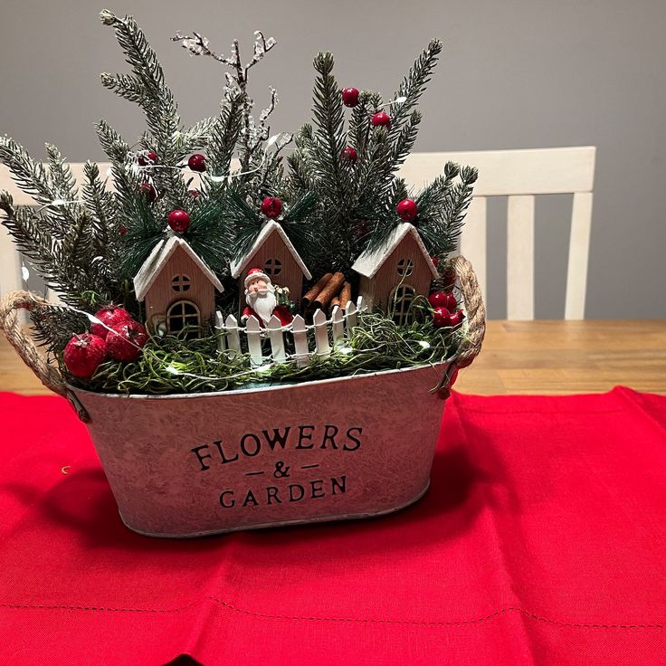 a potted plant with christmas decorations in it on top of a red table cloth