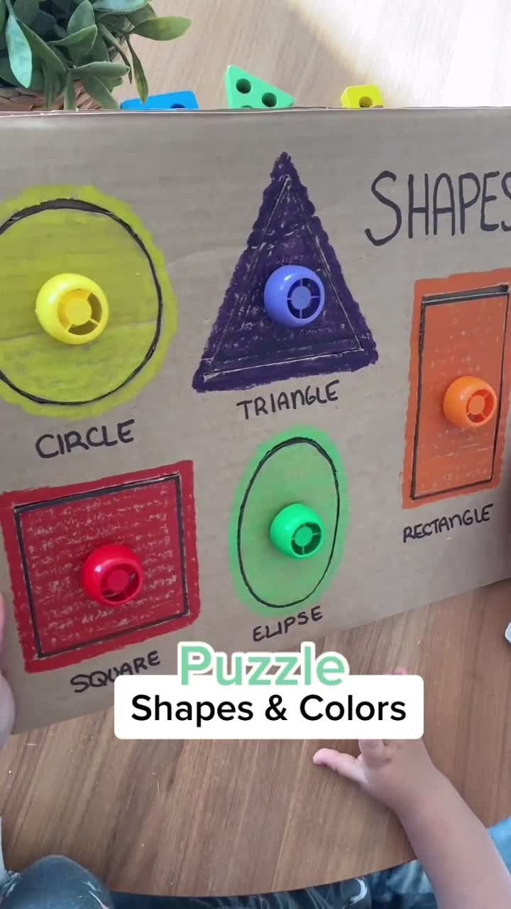 a child is playing with shapes and colors on a cardboard box that says shapes puzzle shapes & colors