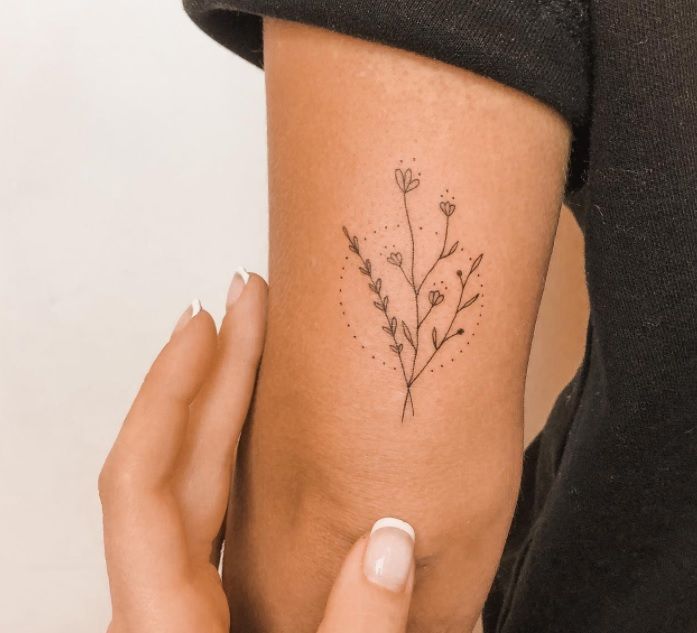 a woman's arm with a small flower tattoo on the left side of her body