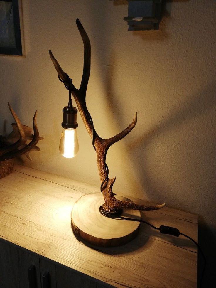 a deer antler lamp sitting on top of a wooden table next to a wall