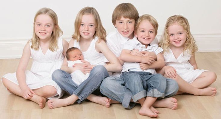 a group of children sitting on the floor with their arms around each other