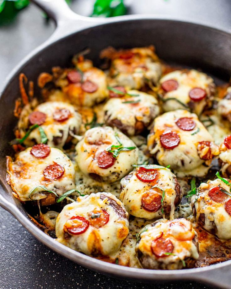 a skillet filled with pizza covered in cheese and pepperoni on top of a table