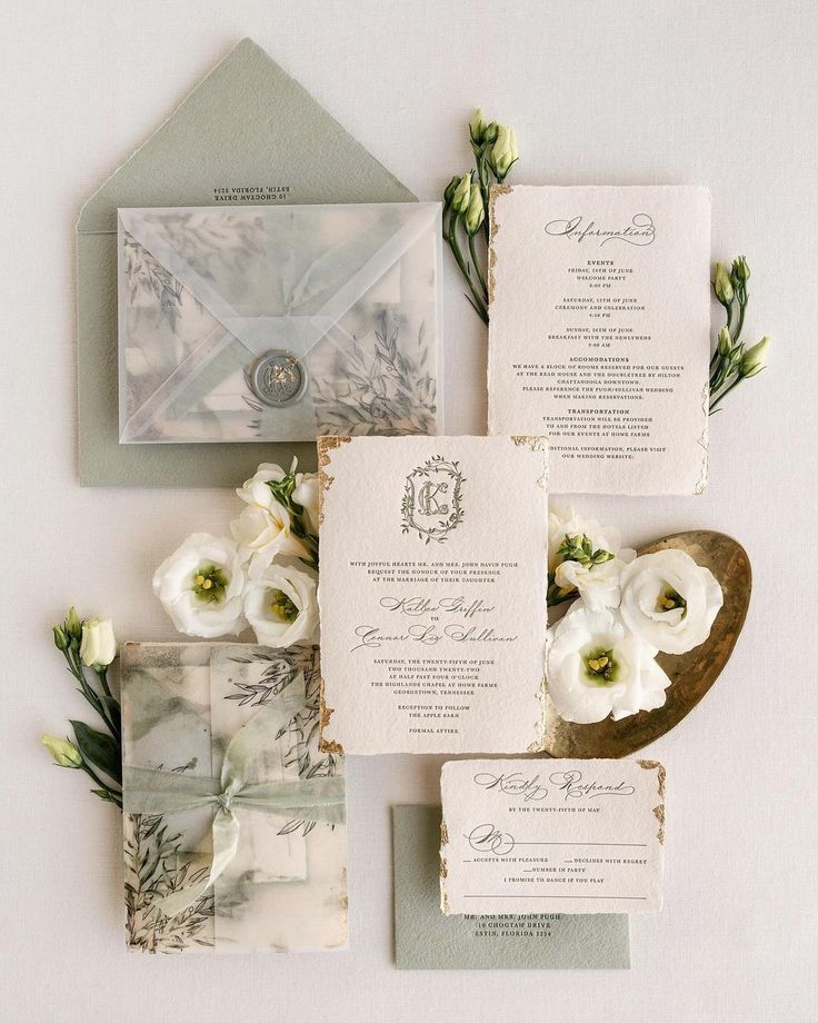 the wedding stationery is laid out on top of each other, with flowers and greenery