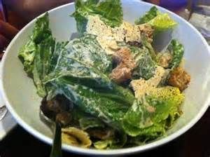 a white bowl filled with lettuce and other food on top of a table