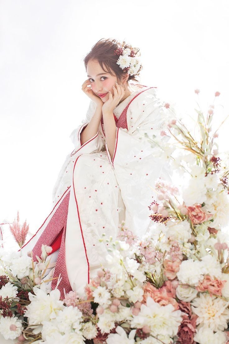 a woman in a white and red kimono surrounded by flowers