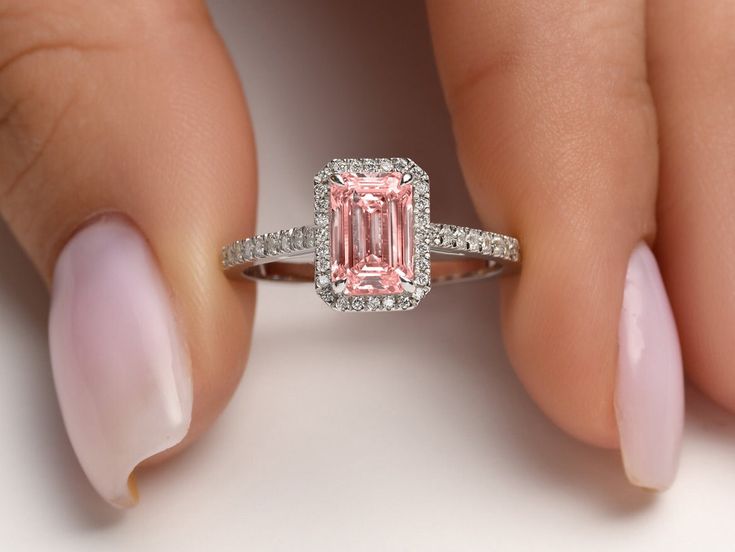 1 Ct Pink Lab Diamond, Emerald Cut Halo, Ring for Women. Stand out from the crown with a timeless diamond ring. This beautiful ring features an elongated, emerald cut 2.37ct diamond paired with tiny diamonds arranged along the band. The band is available in 14K yellow, rose, or white gold. The special occasion ring is a true classic. The emerald cut shape was one of the first diamond ring shapes this is why it is considered a true classic but also a symbol of luxury. Its long, elegant shape and Pink Emerald Cut Engagement Ring, Pink Emerald Cut Ring, Emerald Cut Halo Ring, Diamond Ring Shape, Emerald Cut Halo, Pink Emerald, Emerald Cut Rings, Emerald Engagement Ring Cut, Ring Shapes