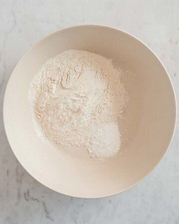 a white bowl filled with flour on top of a marble counter