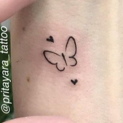 a small butterfly tattoo on the back of a woman's left arm, with hearts in it