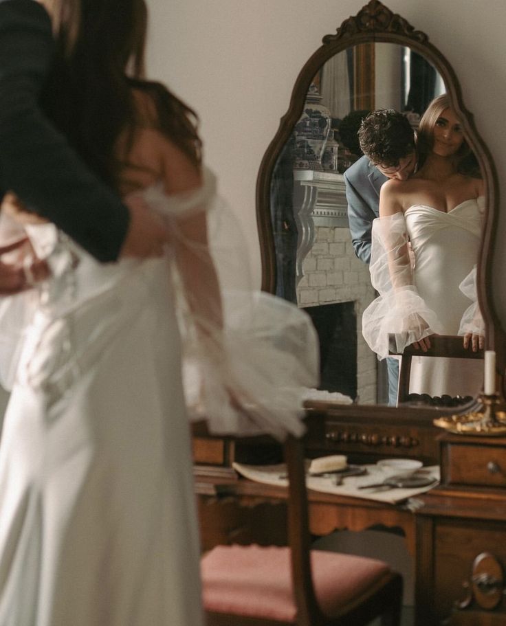 the bride is getting ready to go into her wedding dress in front of the mirror