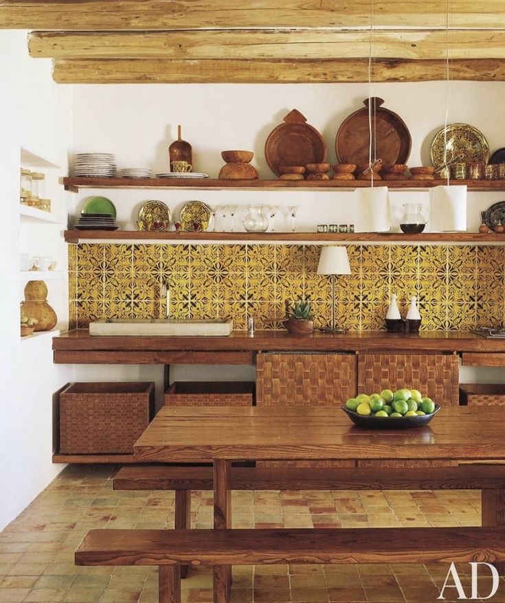 a wooden table sitting under a shelf filled with plates and bowls on top of it