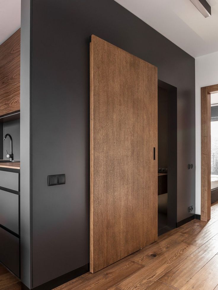 an open door in the middle of a room with wood floors and black painted walls