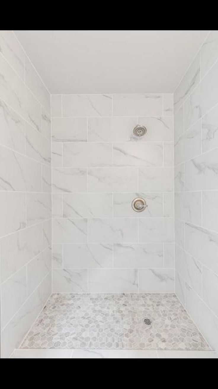 a walk in shower sitting next to a white tiled wall