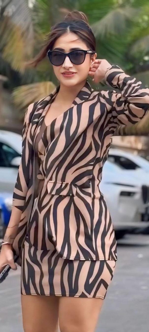 a woman in a zebra print dress is walking down the street with her hand on her hip