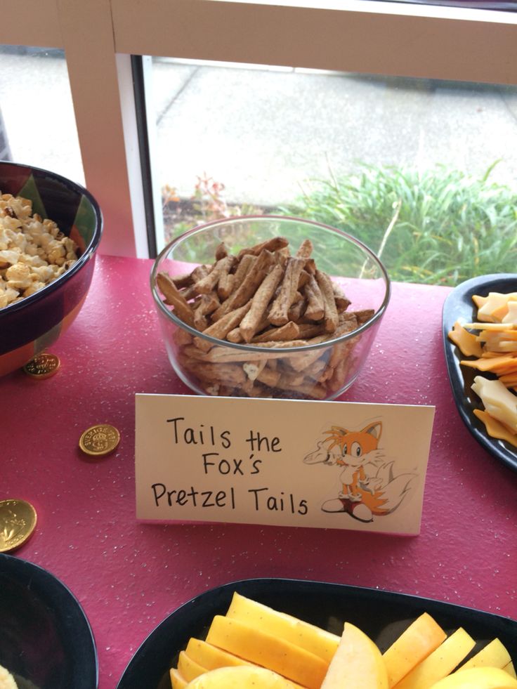 there are many different types of snacks on the table with a sign that says tails the fox pretzel tails