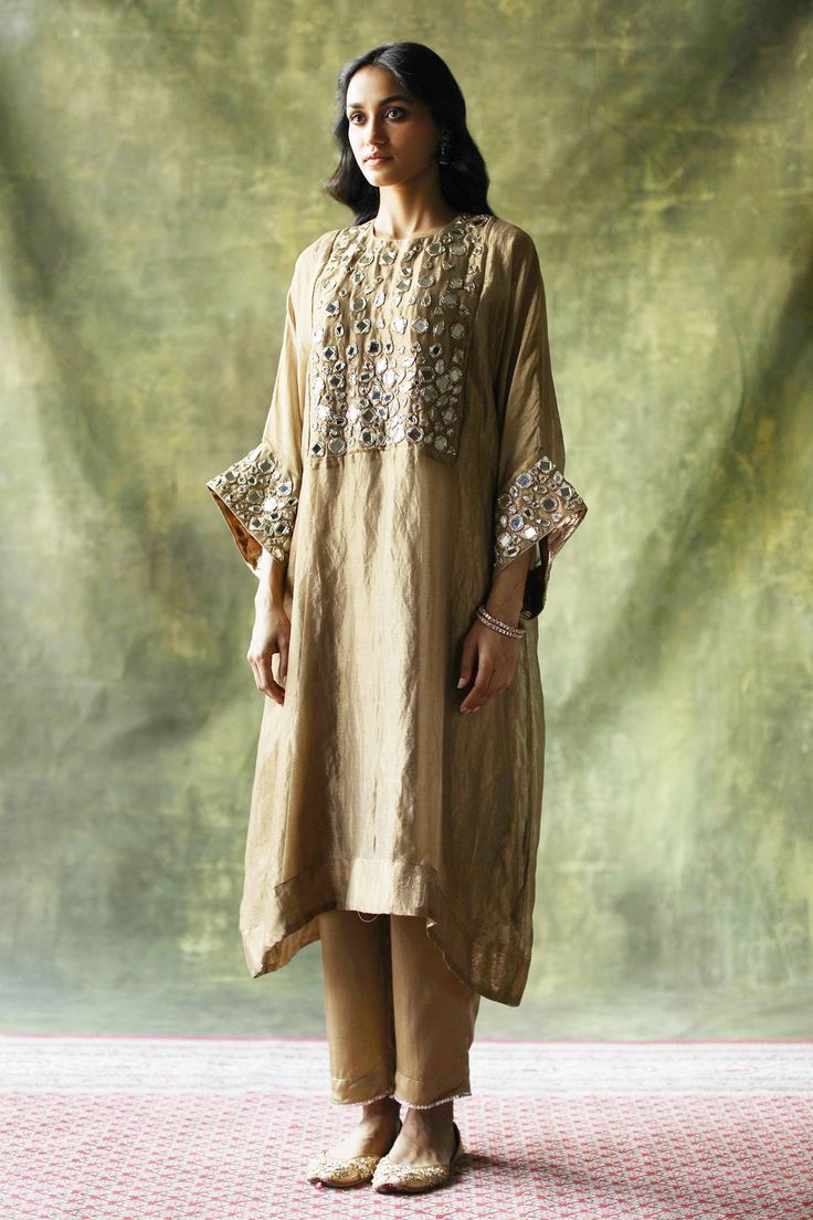 Beige zari silk kaftan kurta embellished with mirror work across the yoke and sleeves. Come with pants with mirror finished trims and a slip.
Component: 3
Pattern: Embroidery
Type Of Work: Mirror work
Neckline: Round
Sleeve Type: Loose sleeves
Fabric: Kurta: Zari Silk, Slip: Satin, Pant: Modal Satin
Color: Beige
Other Details: 
Mirror work
Zari silk kurta
Occasion: Mehendi and Haldi - Aza Fashions Luxury Art Silk Kurta For Formal Occasions, Luxury Traditional Kurta With Sequins, Luxury Straight Kurta Kaftan For Eid, Luxury Chinon Traditional Wear With Mirror Work, Luxury Elegant Kurta With Pallu, Luxury Long Bohemian Kurta, Luxury Formal Kurta With Motifs, Luxury Traditional Eid Pants, Luxury Anarkali Set With Mirror Work For Eid