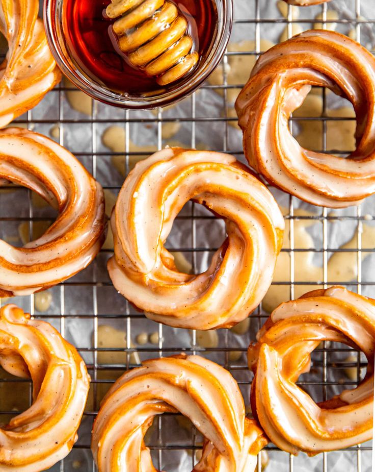 several pretzels on a cooling rack with honey in the middle and one being drizzled with icing