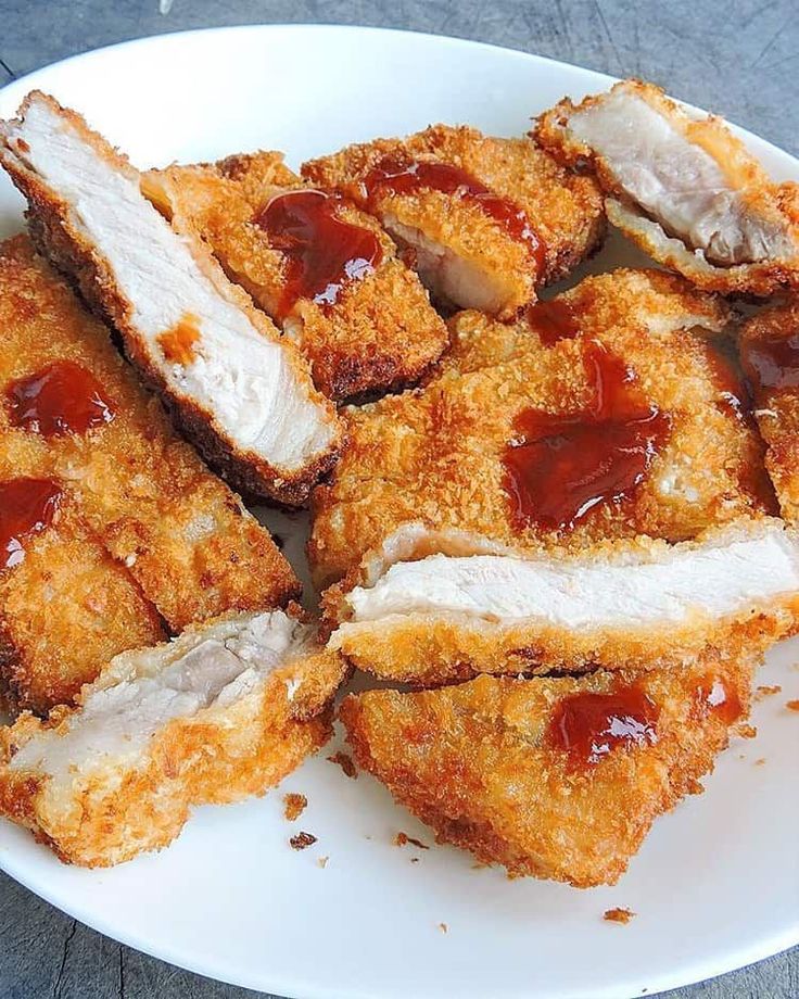 several pieces of fried chicken on a white plate with ketchup and mayonnaise