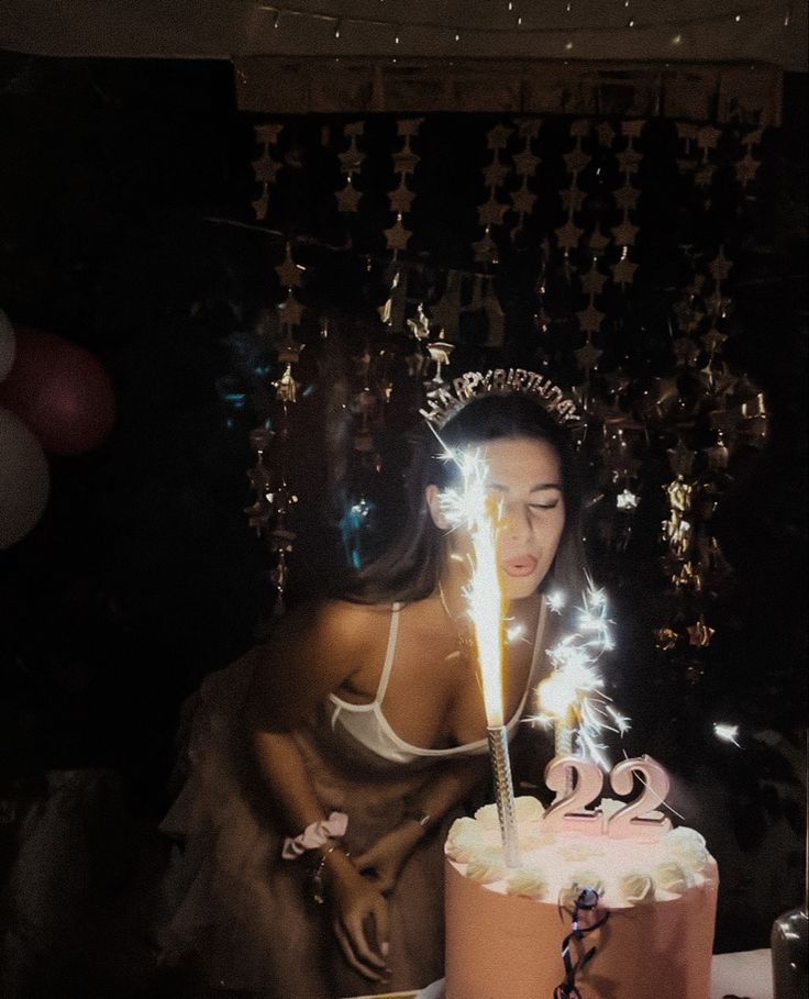 a woman with a tiara blowing out sparklers on her birthday cake while wearing a bra