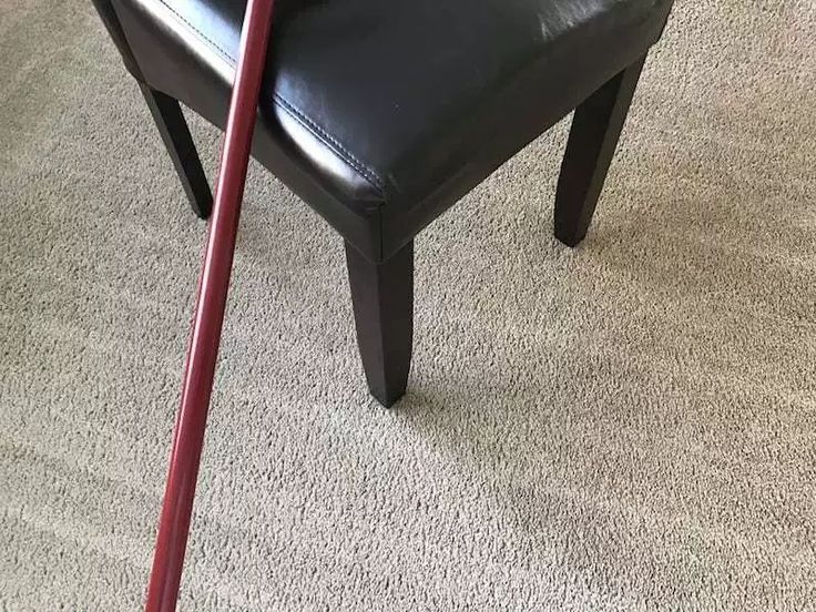 a black chair with a red stick sticking out of it's seat and carpet