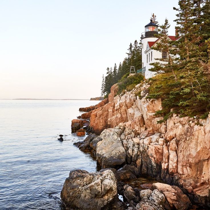 a light house sitting on top of a rocky cliff next to the ocean and trees