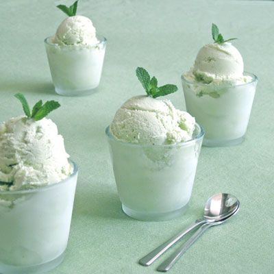 four ice creams with mint sprigs in small glass cups on a green tablecloth