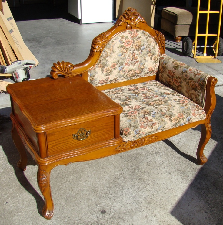 an antique wooden couch with floral upholster and matching foot rest on concrete flooring