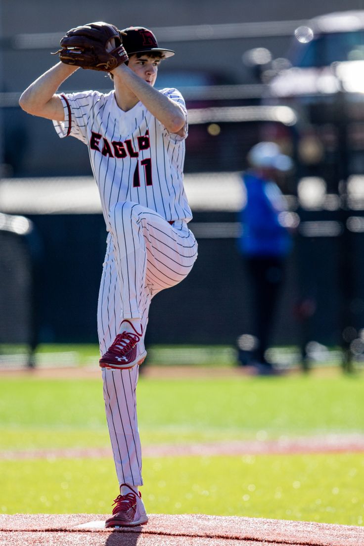 a baseball player pitching a ball on top of a field with other players in the background