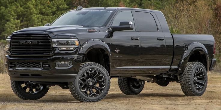 a large black truck parked on top of a dirt field