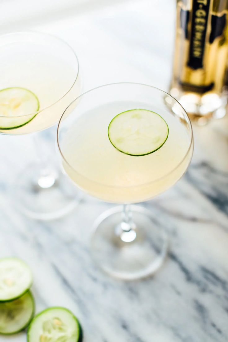 two glasses filled with cucumber martinis on a table