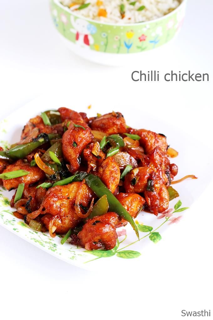 chicken wings with green peppers and rice in a bowl next to it on a plate