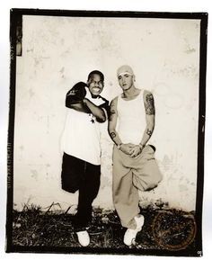 two men standing next to each other in front of a wall