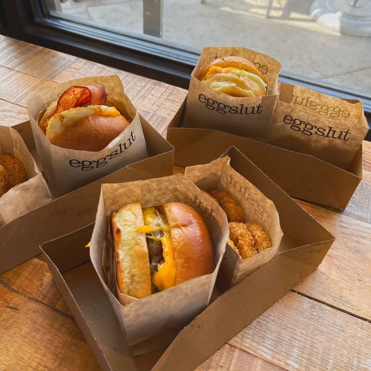 four boxes filled with different types of food on top of a wooden table next to a window