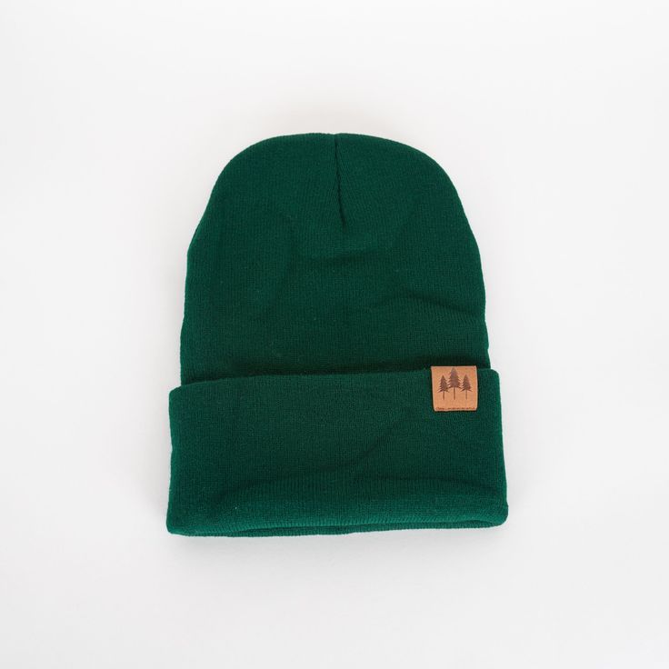 "Add a touch of nature with our Three Tree Foldover Beanie - Emerald. Featuring a suede small patch and a stylish fold over design, this beanie will keep you cozy and on trend. Perfect for chilly days and adventurous souls." One size fits all. A Montana Scene Original Design. All designs are property of The Montana Scene. All rights reserved.All of The Montana Scene apparel is designed and printed locally in Montana. Come visit our storefront locations! Bigfork * Whitefish * Missoula * Kalispell Fall Green Cotton Hat, Adjustable Solid Beanie For Outdoor, Cozy Hats With Fleece Lining For Fall, Trendy Outdoor Beanie One Size, Green Winter Hat For Everyday Use, Warm Hat For Outdoor Fall Use, Trendy One Size Beanie For Outdoor, Green Beanie For Cold Weather, Warm Green Casual Beanie