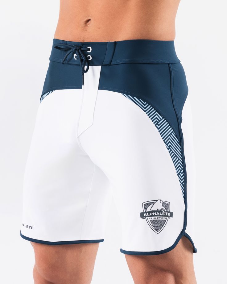 HIGHLIGHTS.. Unlined boardshort. 9” inseam Reflective branding at leg opening and back waistband Elastic waistband with adjustable self-tie drawcords Color-blocking panelling Water resistant fabric FIT SUGGESTION. This item runs true to Alphalete’s standard sizing.. Fit is based off of waist size in inches.. If you are between sizes, we recommend sizing up for a relaxed fit.. Eric is 6’2”/188cm, wearing a size 32. MATERIALS AND WASHING DIRECTIONS. 67% Nylon, 23% spandex. Due to the high saturati White Bottoms With Contoured Waistband For Summer, Summer White Bottoms With Contoured Waistband, White Surfing Swim Trunks, Fitted White Swim Trunks For Surfing, White Fitted Swim Trunks For Surfing, White Swimming Bottoms With Built-in Shorts, White Training Bottoms With Elastic Side Panels, Sporty White Athletic Shorts With Drawstring, White Athleisure Bottoms With Functional Drawstring