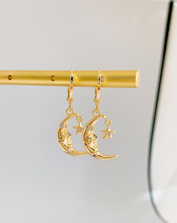 Radiate celestial elegance with The Moon Goddess Huggie Earrings. These earrings capture the allure of lunar beauty in a mesmerizing design. Meticulously crafted, the mini moon and goddess charms exude a sense of ethereal grace and power. The huggie style ensures a secure fit, promising comfort throughout the day. Whether you're drawn to cosmic mystique or seek unique accessories, these earrings make a statement. Perfect for both casual outings and special occasions, they infuse your ensemble wi Gold Half Moon Celestial Earrings, Dainty Gold Earrings With Moon Phase, Celestial Crescent Single Earring, Celestial Half Moon Single Earring, Gold Moon Phase Earrings, Single Crescent Celestial Earring, Gold Half Moon Earrings With Moon Charm, Celestial Moon Charm Earrings As Gift, Celestial Moon Charm Earrings For Gift