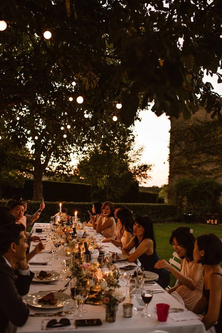 a group of people sitting at a long table with food and wine glasses on it