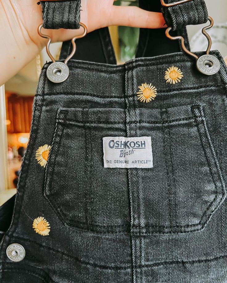 someone is holding onto the back of their overalls with sunflower patches on them