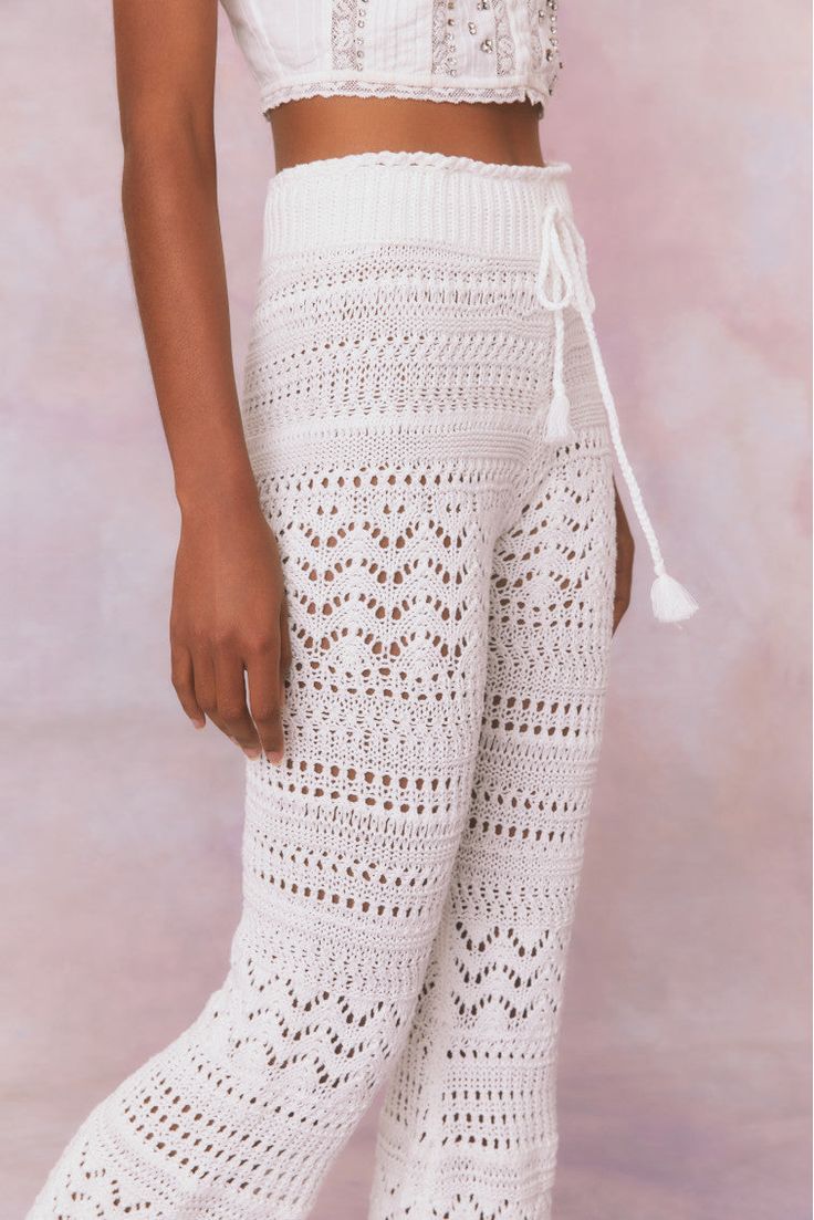 Feeling cute in the Fosta Pant. Designed from 100% cotton, the pretty crochet pants stun with mixed pointelles, crochet insets, and dimensional florals all over. With a flare fit, the boho-inspired pants fit slim throughout the hip and upper leg before descending to an open, airy bottom. A double ribbed waistband gives these pants a flattering fit and are finished with a self tie detail at center front. Pair with our Middleton Cardigan for a full set. Crochet Pants Pattern, Crochet Bottoms, Pretty Crochet, Crochet Fairy, Crochet Pants, Lace Pants, Pink Sale, Pants Fit, Fleece Sweater