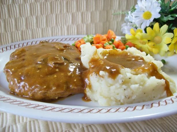 a white plate topped with mashed potatoes covered in gravy and gravy