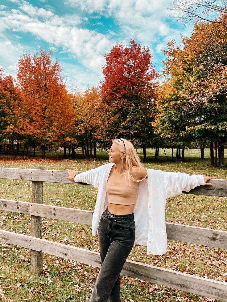 a woman leaning on a fence with her arms spread out in front of the camera