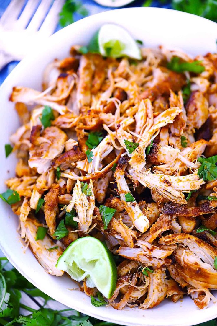 a white bowl filled with shredded chicken and garnished with cilantro