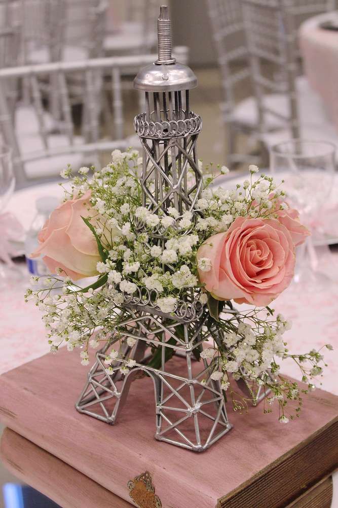 the eiffel tower centerpiece is adorned with pink roses and baby's breath