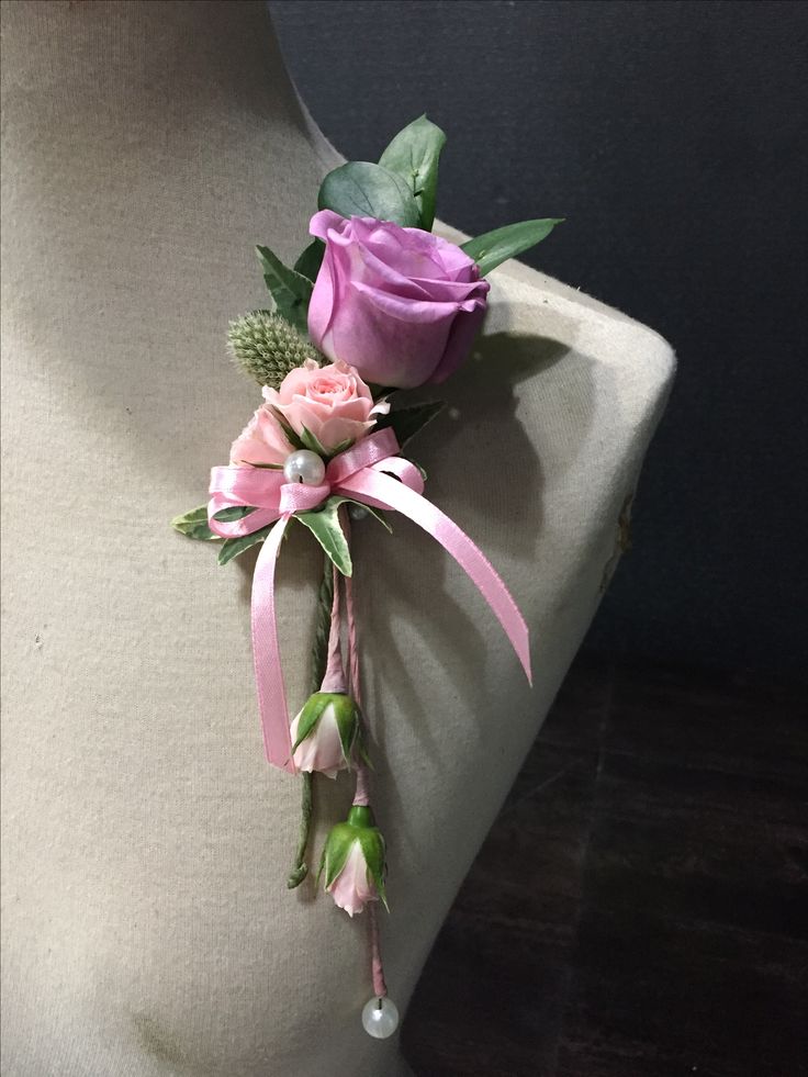 a boutonniere with pink roses and greenery on a mannequin