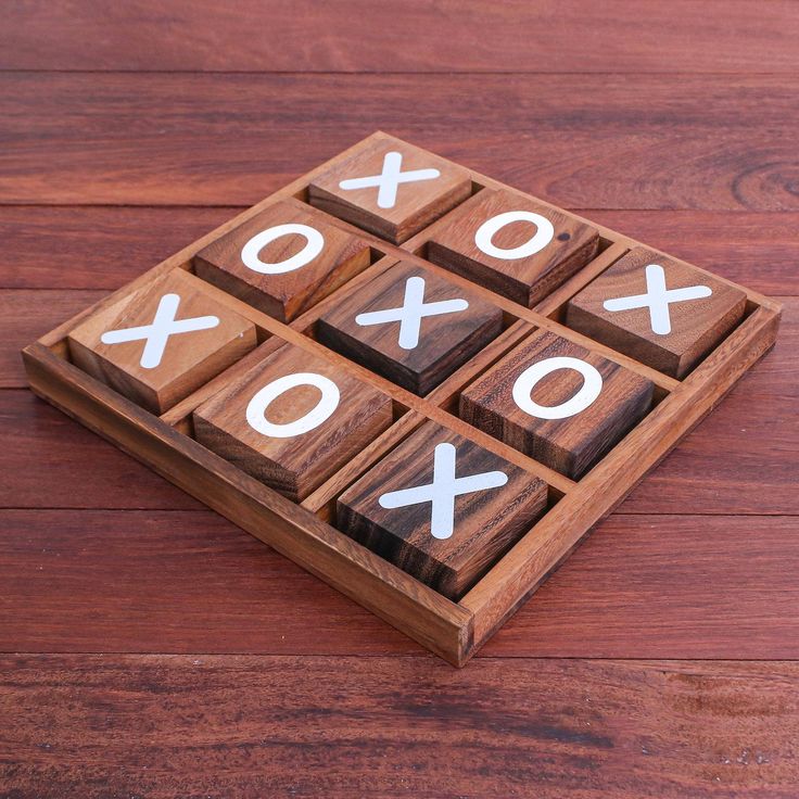 wooden tic - tac - toe game with white crosses on it sitting on a wood surface