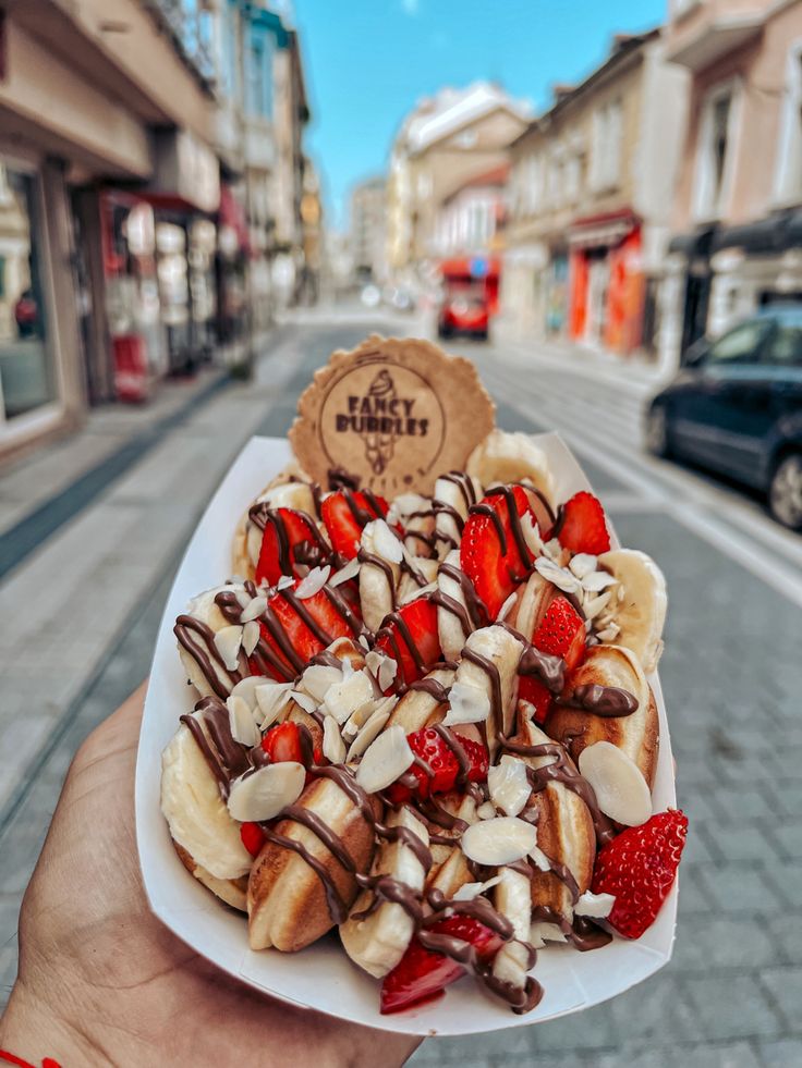 a person holding up a plate with bananas and strawberries on it in the street