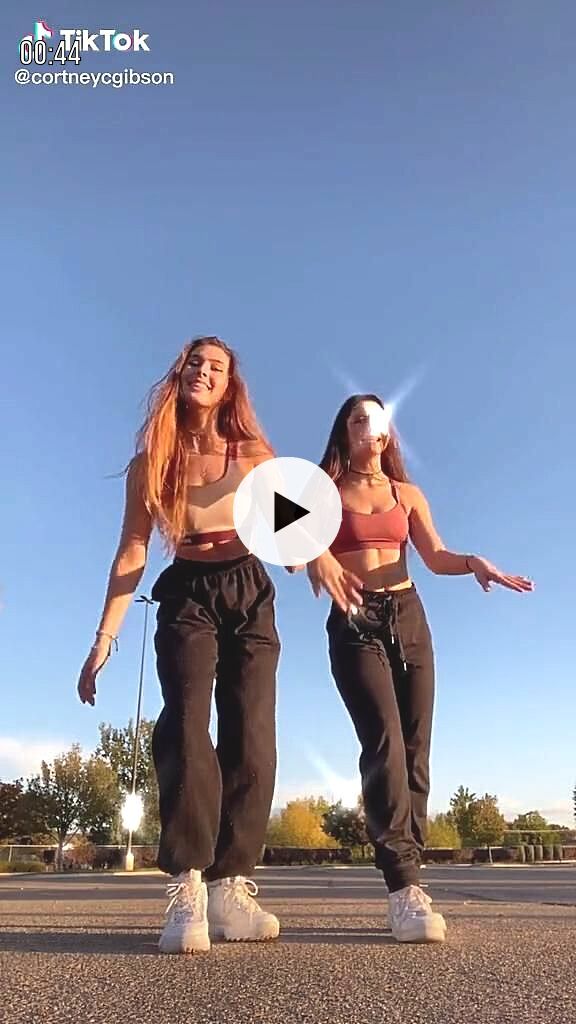 two women are dancing on the street together