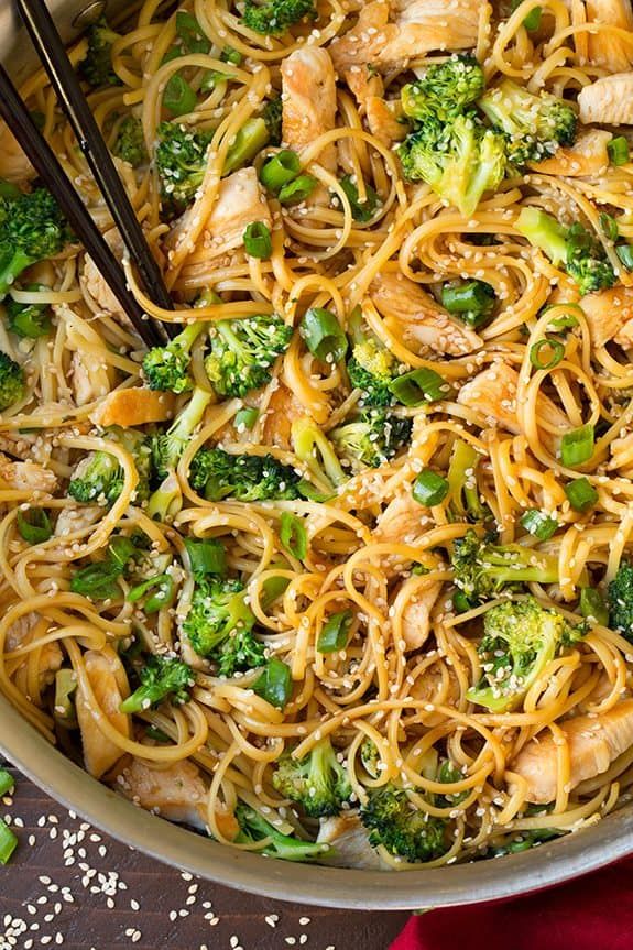 chicken and broccoli lo mein in a pan with chopsticks on the side